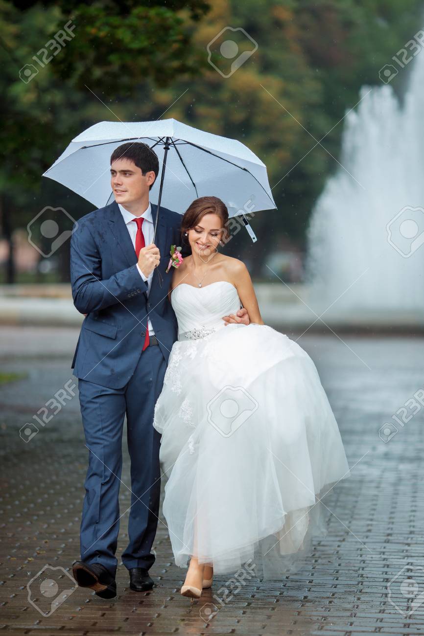 Happy Wedding Couple In A Rainy Wedding Day Outdoors In Park