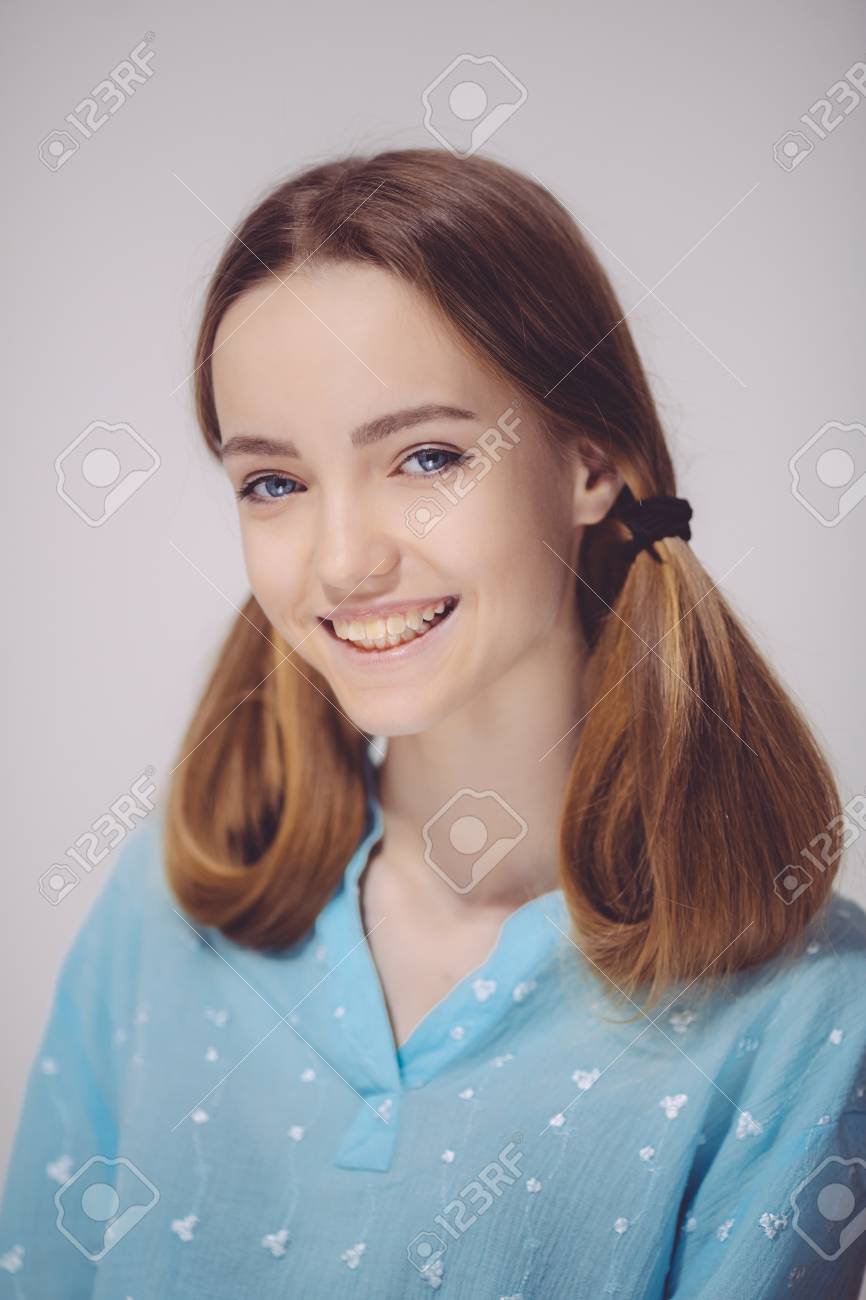 幸せな表情でカメラをトップ金髪 10 代女の子の健康な皮膚を着て青見て笑っている若者の肖像画 屋内で白人ティーン女性モデルポーズ の写真素材 画像素材 Image