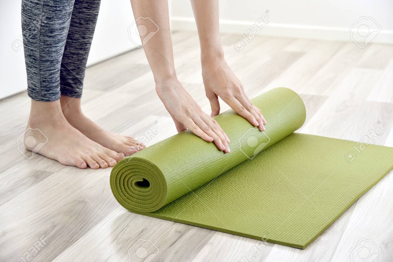 Woman Folding Yoga Or Fitness Mat After Working Out At Home