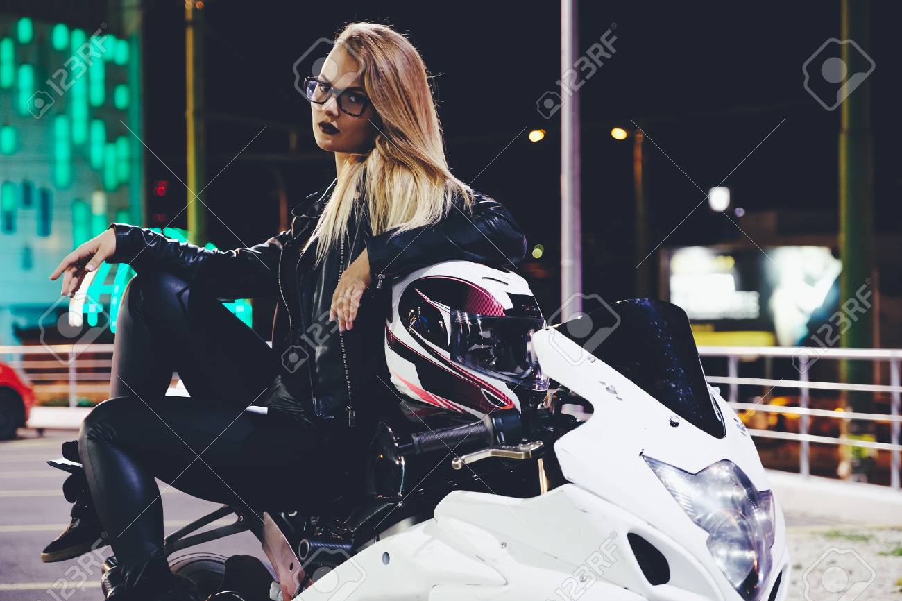 白いバイクに革の服でバイクに乗る女の子 セクシーな若い女性のバイカーが彼女のバイクに座っています 概念冒険 都市の夜景 の写真素材 画像素材 Image