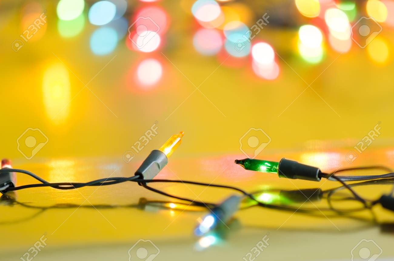 Lampadine Di Natale Sulla Corda In Pi¹ Colori Blu Giallo Verde Rosa E Rosso Su Sfondo Giallo Oro Con Copia Spazio E Bokeh luci Sfocate Per Natale