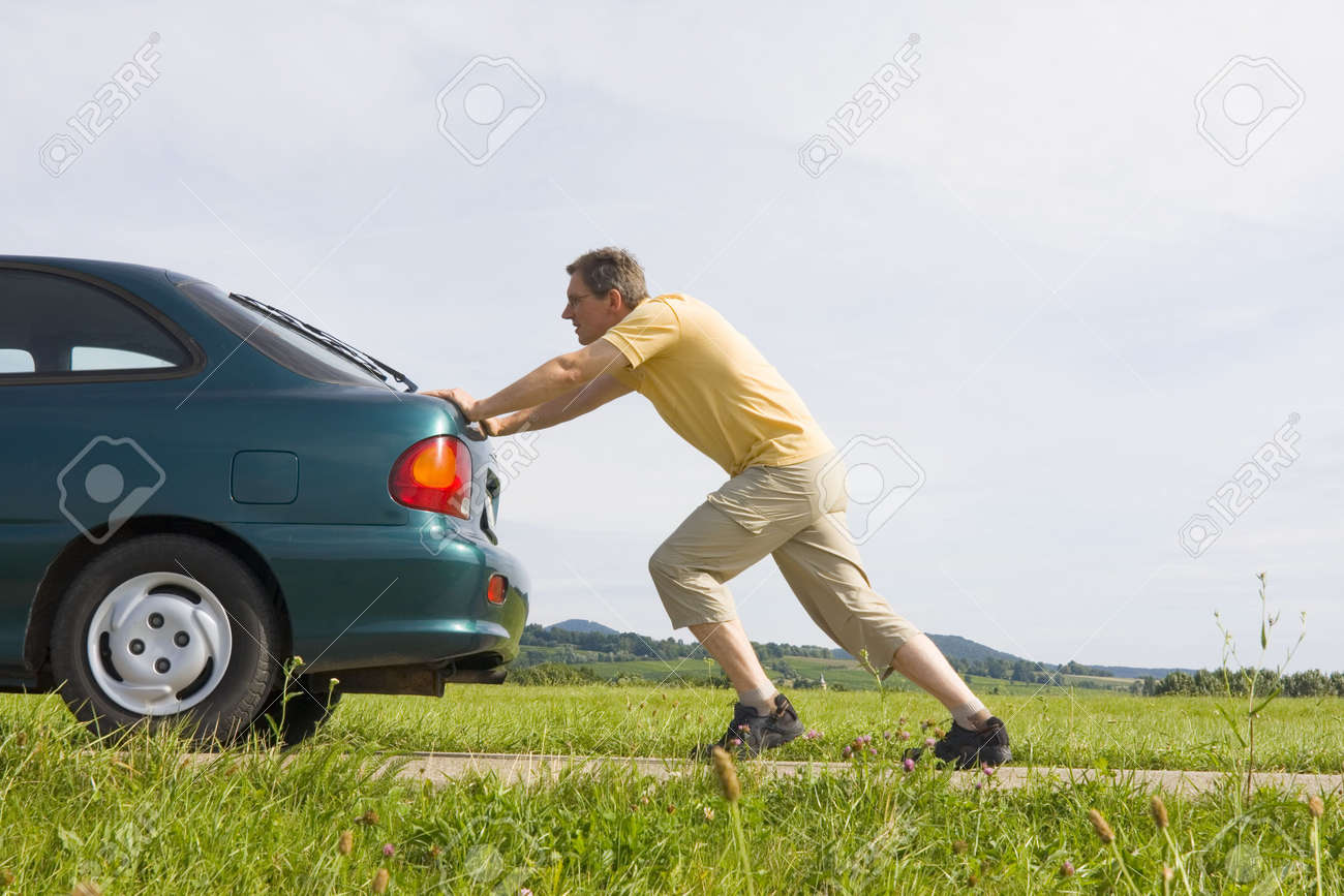 man pushing a car with empty gas tank stock photo picture and