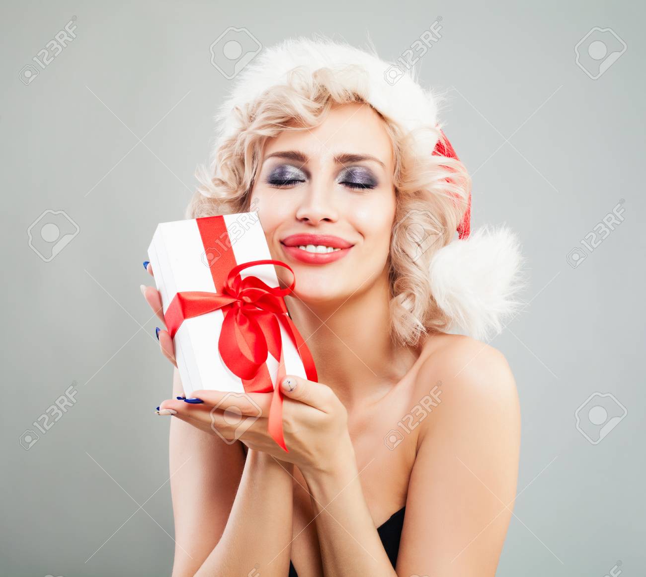 サンタの帽子を抱いてホワイト クリスマスのクリスマスの女の子ギフト ボックス ブロンドの髪 メイクやクリスマス プレゼントで幸せなモデル 新年や クリスマスのコンセプト の写真素材 画像素材 Image