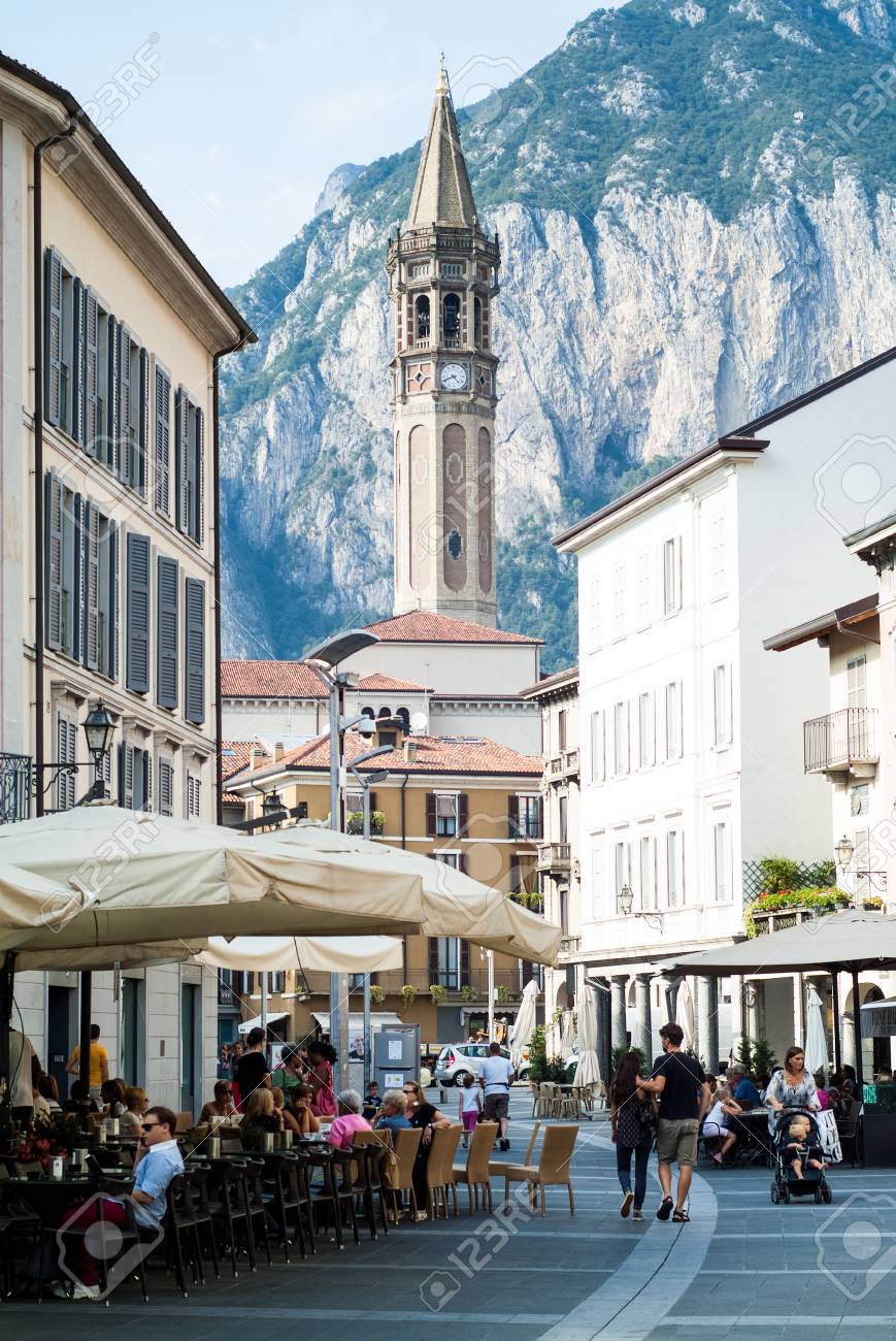 Lecco, Italy - September 1st, 2015: People Enjoying Themselves In Piazza XX  Settembre On September 1st, 2015, In Lecco, Italy, With Basilica Of Saint  Nicholas (Campanile Di San NicolÃ²) Visible In The, image size:869x1300