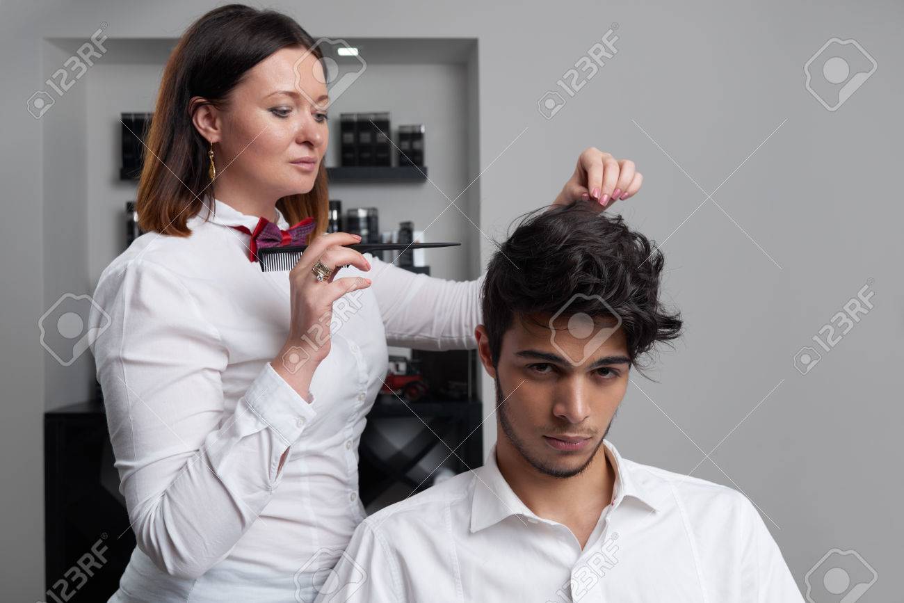 the professional hairstylist is brushing the clients hair with brush and making nice hairdo stock photo