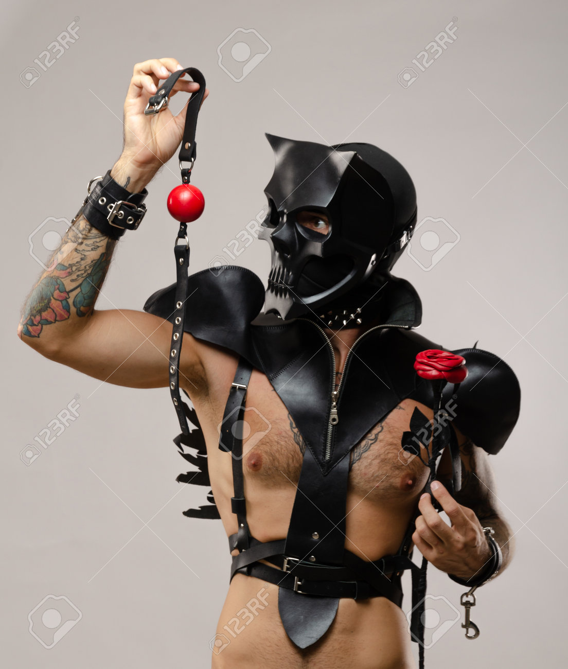 緊縛　革 体に革のブレスレットとストラップが付いた革のマントに身を包んだ、ギャグを持った頭蓋骨の悪魔の緊縛マスクの男の写真素材・画像素材 Image  174254710