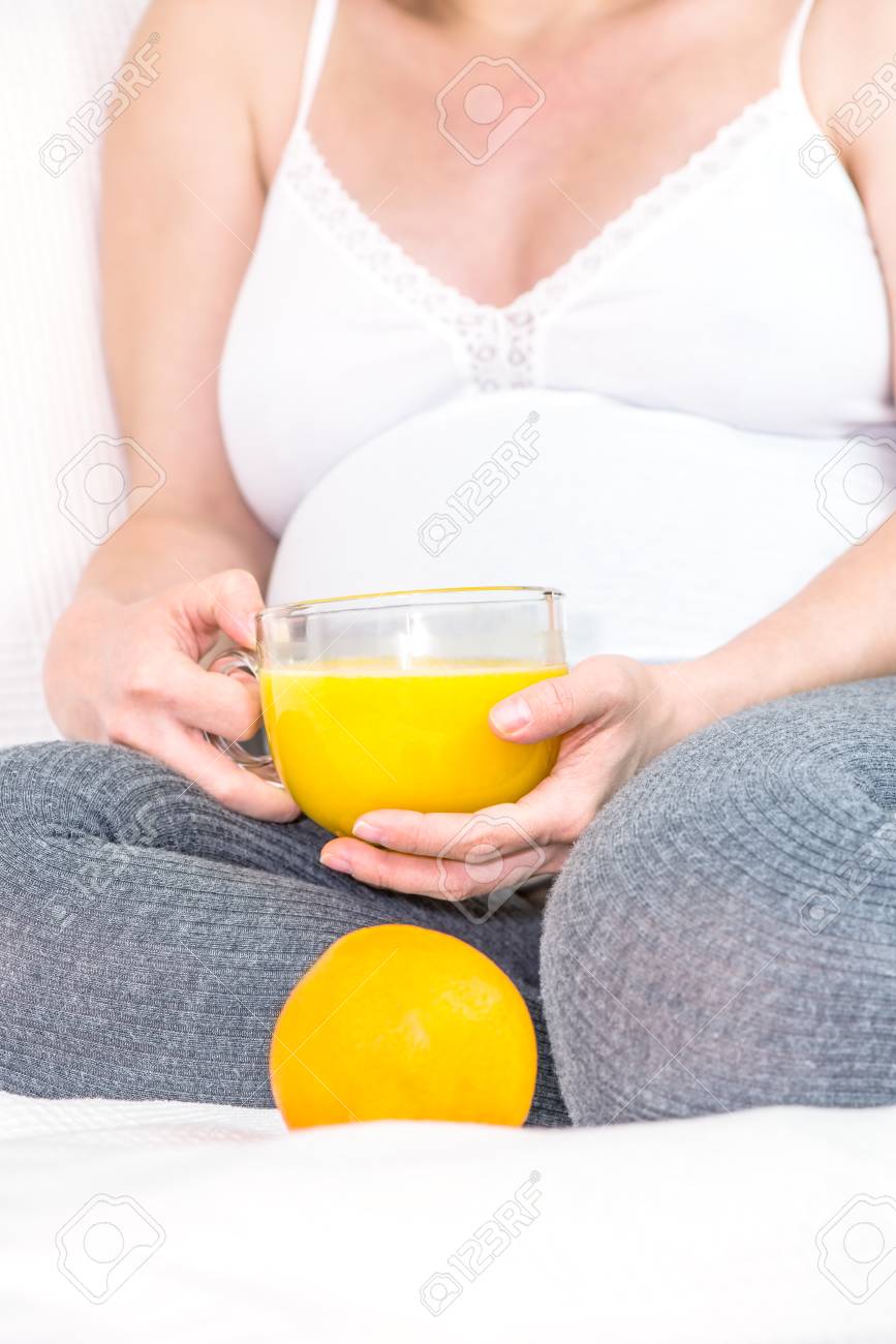 オレンジ ジュースとマグカップを保持している妊娠中の女性 の写真素材 画像素材 Image