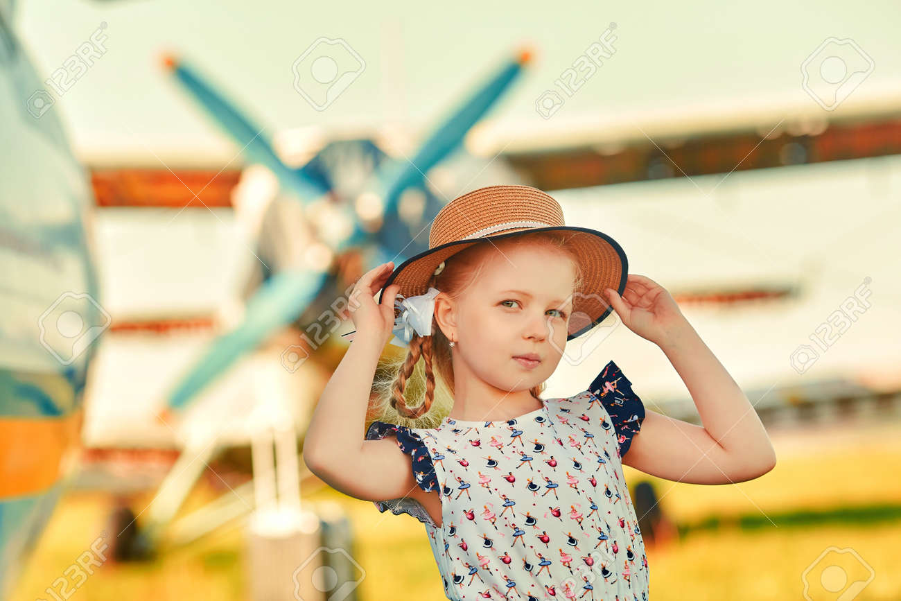 A cute child in a romantic hat stands on the tarmac, aircraft propellers in the background. The concept of dreams about traveling - 158561737 A cute child in a romantic hat stands on the tarmac, aircraft propellers in the background. The concept of dreams about traveling - 158561737
