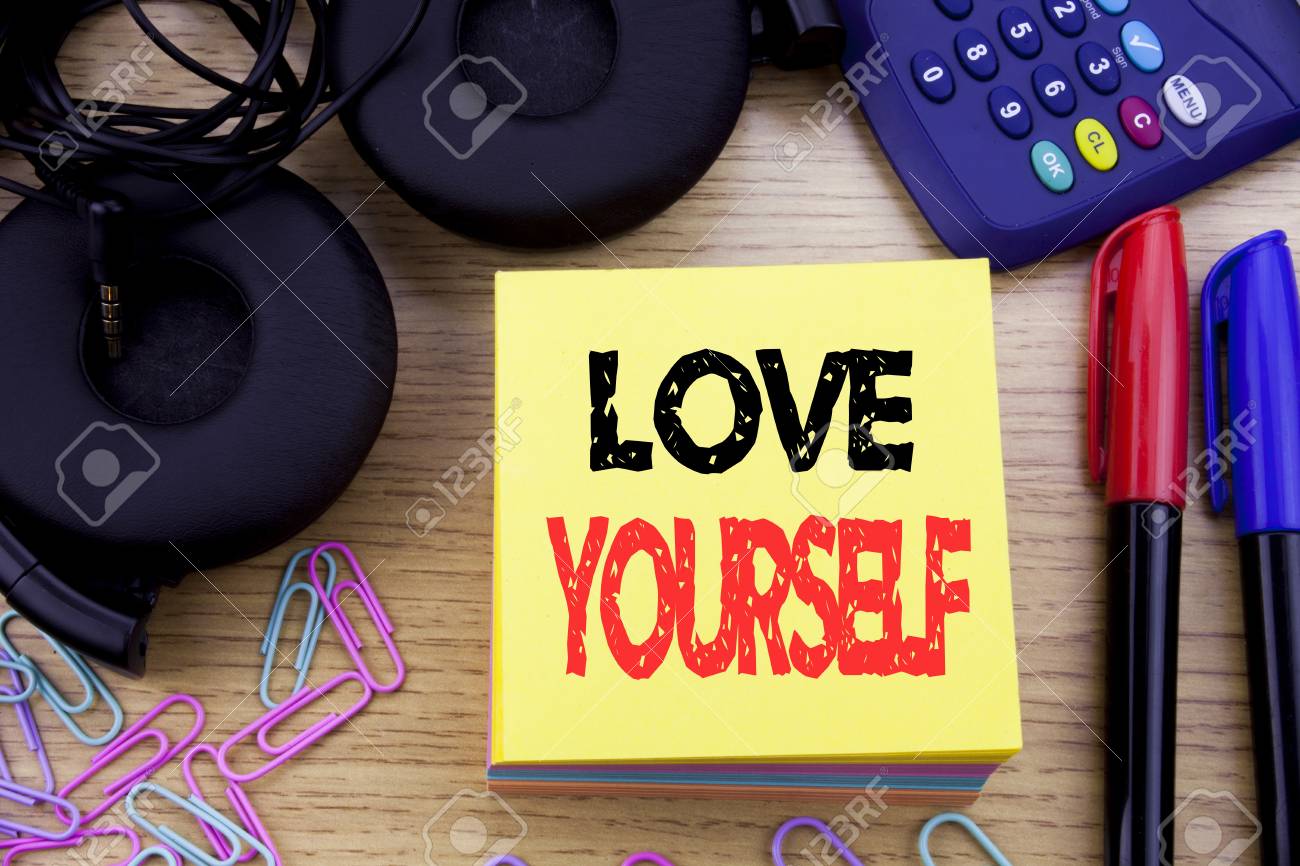 言葉 自分を愛する 木製の背景に付箋紙に書かれたポジティブスローガンのためのビジネスコンセプト 電卓とペンマーカーとヘッドフォン付き の写真素材 画像素材 Image