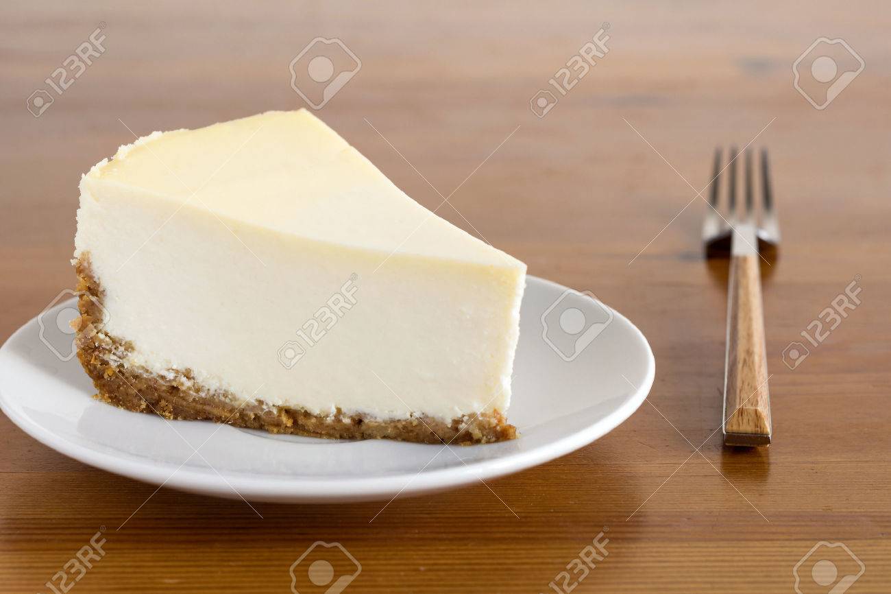 Slice Of Plain New York Cheesecake On White Plate On Wooden
