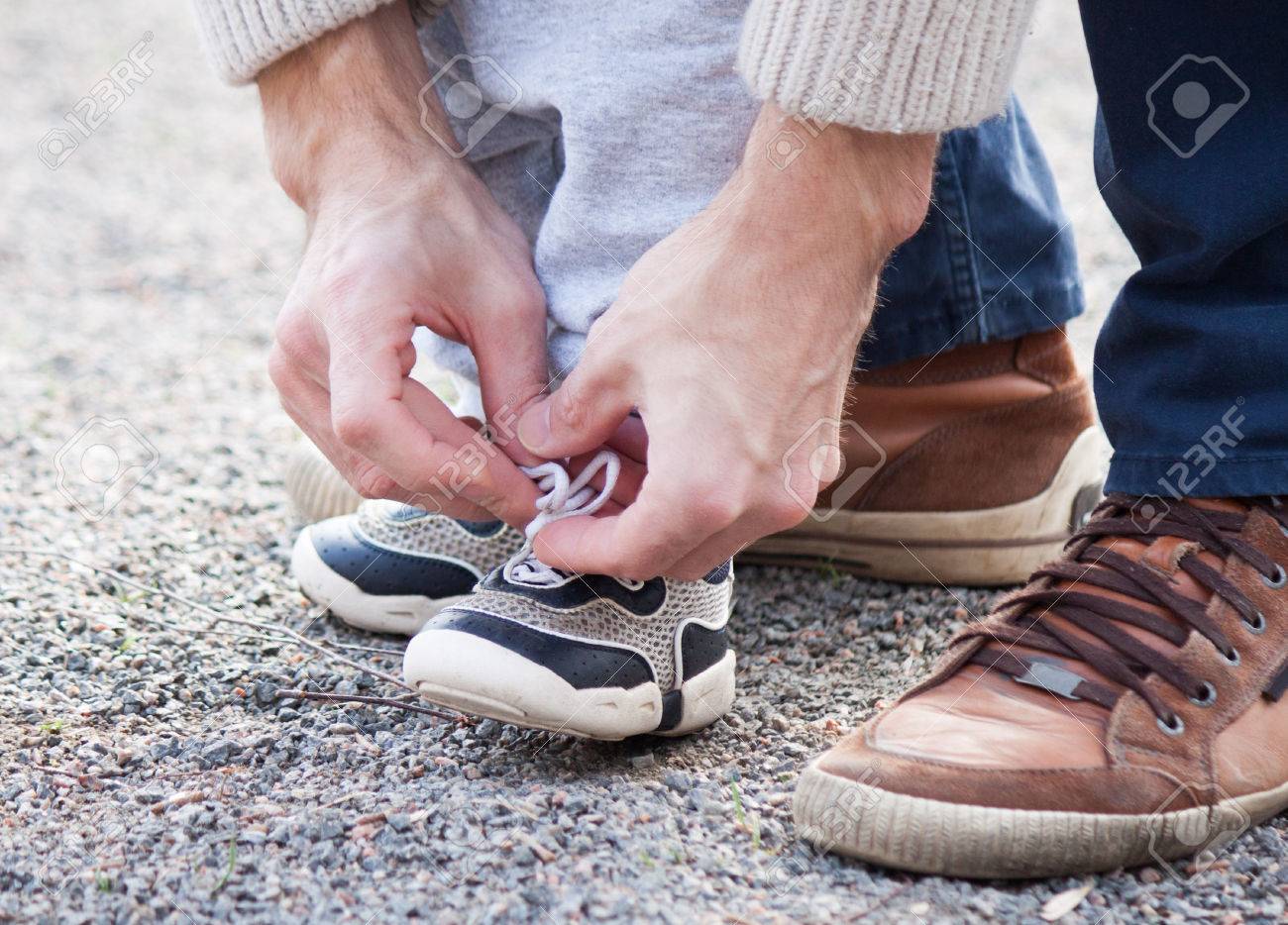 Dad tying the laces on a child sneakers - 55042598 Dad tying the laces on a child sneakers - 55042598