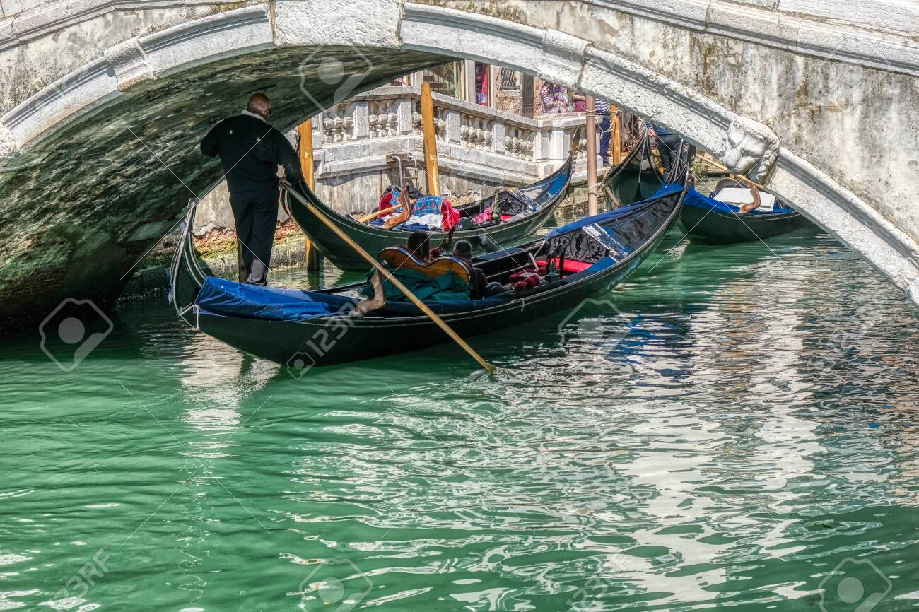 Venice, Italy - April 17 2019: Gondola passing below one of many bridges in Venice, Italy - 137009125 Venice, Italy - April 17 2019: Gondola passing below one of many bridges in Venice, Italy - 137009125