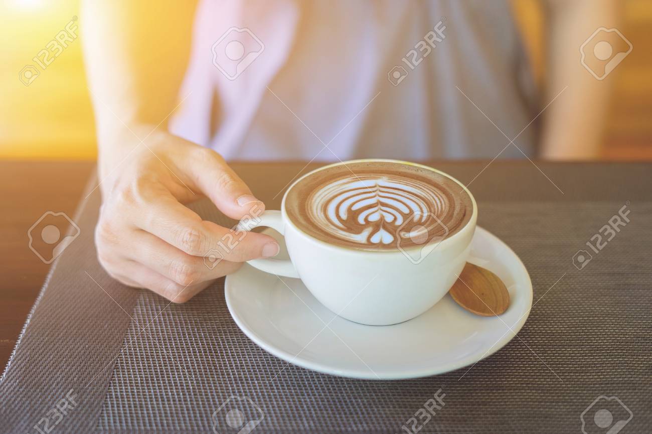 女性の座っていると彼女の仕事の休憩中に彼女の暇な時 モダンなカフェで素敵なビジネス女性のランチを楽しみながらコーヒー ショップ ウィンドウで素朴な木製のテーブル背景にコーヒーのホットカップを保持 の写真素材 画像素材 Image