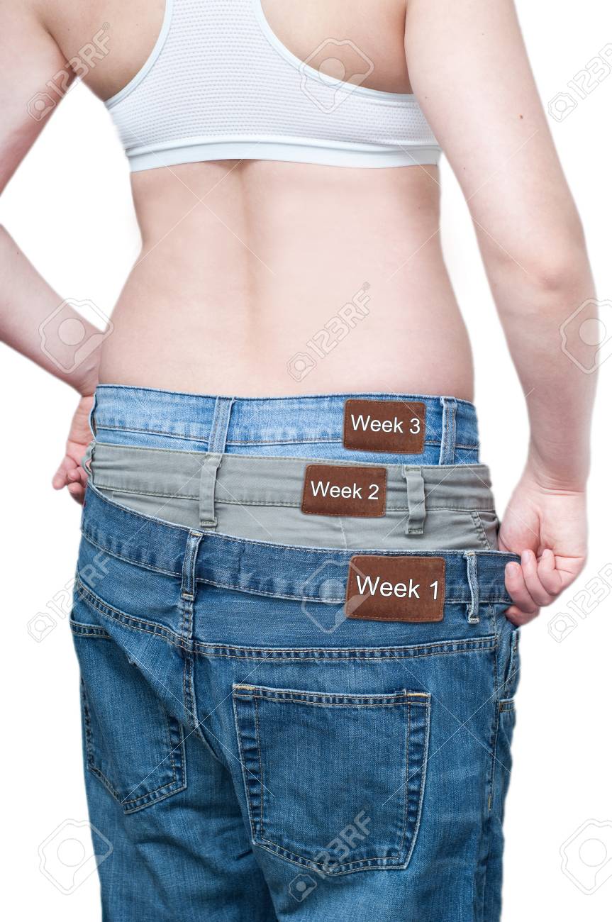 yuong woman monitoring weekly weight loss by wearing tree jeans