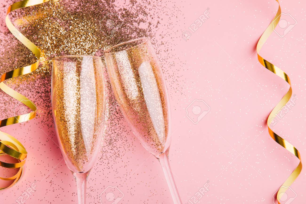 Two glasses of champagne toasting with golden confetti, glitter and serpentine on a pink background. Flat lay. Night of celebration concept - 109282271 Two glasses of champagne toasting with golden confetti, glitter and serpentine on a pink background. Flat lay. Night of celebration concept - 109282271