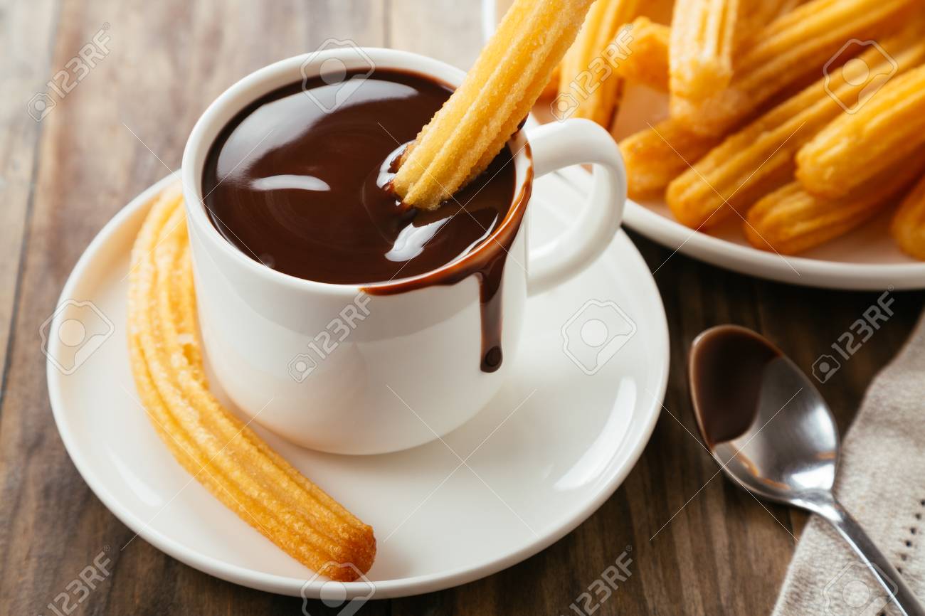 Traditional spanish churros with hot chocolate sauce on a rustic wooden table - 112463478 Traditional spanish churros with hot chocolate sauce on a rustic wooden table - 112463478