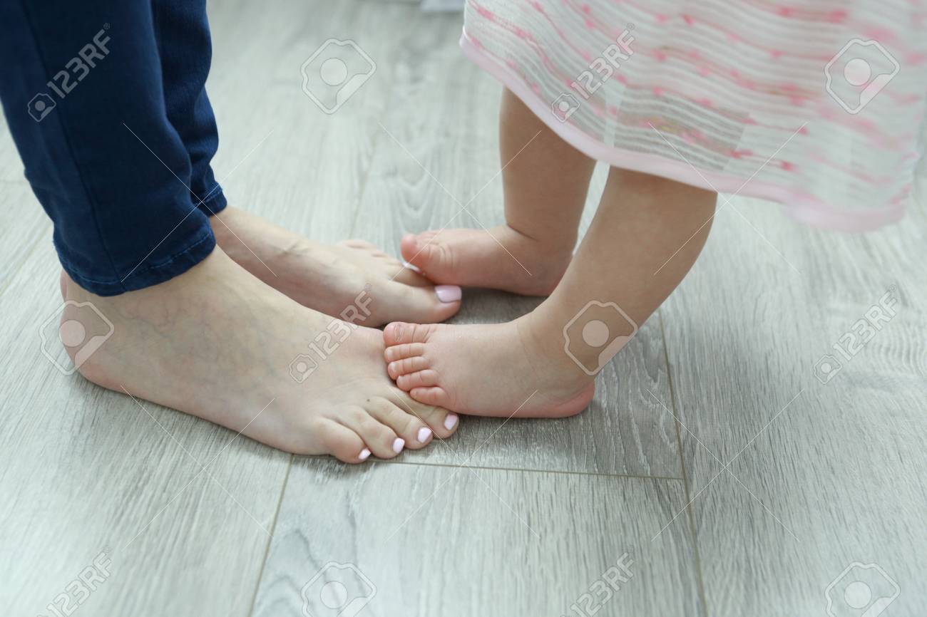 赤ちゃんのママの足で立っています ママと娘の足のクローズ アップ の写真素材 画像素材 Image