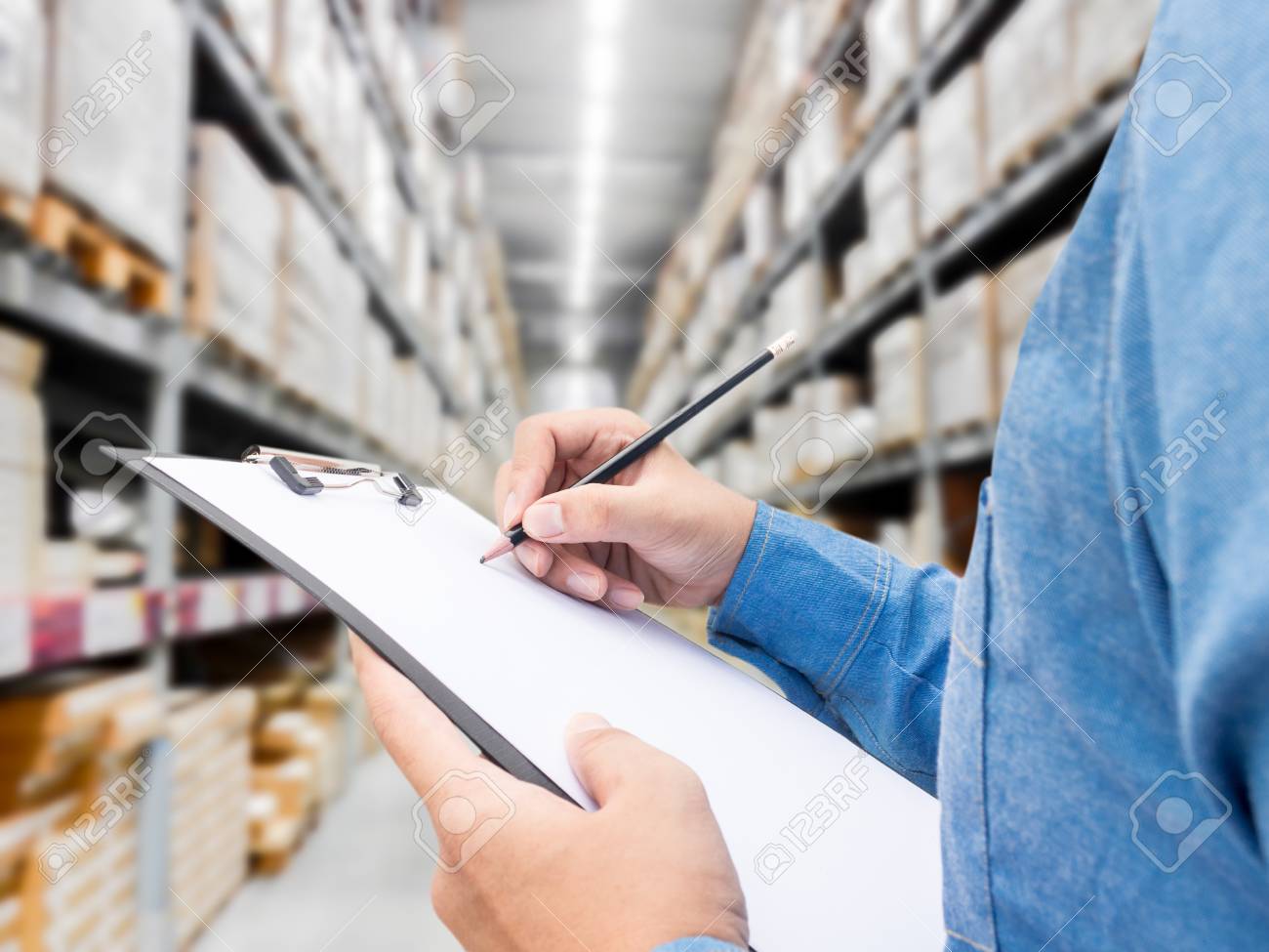Man checking list on clipboard in a warehouse - 88438320 Man checking list on clipboard in a warehouse - 88438320