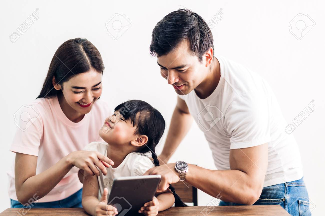 Happy family father and mother with daughter sitting and looking at tablet computer together in the living room at home - 124760372 Happy family father and mother with daughter sitting and looking at tablet computer together in the living room at home - 124760372
