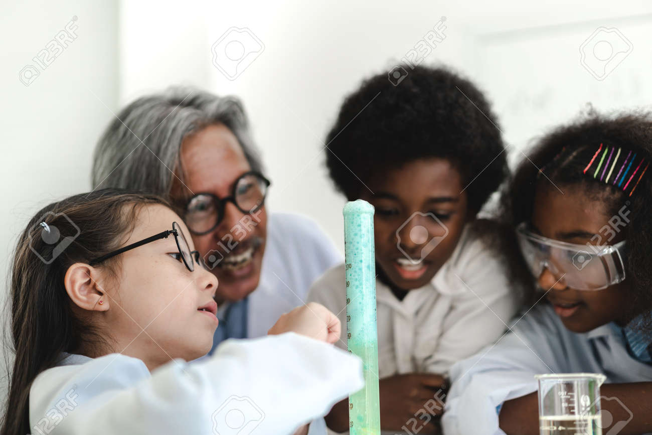Group of teenage students learning and doing a chemical experiment and holding test tube in hands in the experiment laboratory class on table at school.Education concept - 168607001 Group of teenage students learning and doing a chemical experiment and holding test tube in hands in the experiment laboratory class on table at school.Education concept - 168607001