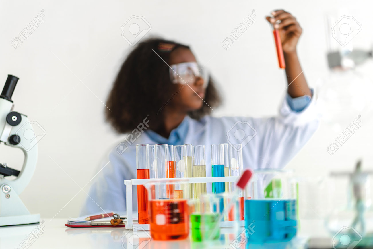 African american girl students learning and doing a chemical experiment and holding test tube in hands in science class on the table.Education concept - 168607007 African american girl students learning and doing a chemical experiment and holding test tube in hands in science class on the table.Education concept - 168607007