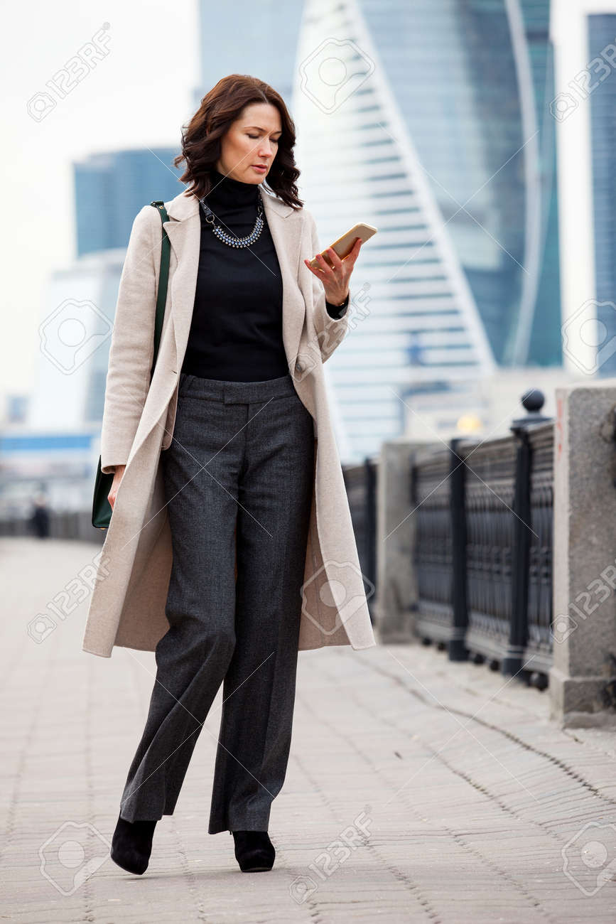 Fashionable Beautiful Middle Aged Woman In A Light Overcoat Messaging Stock Photo Picture And Royalty Free Image Image 60129386