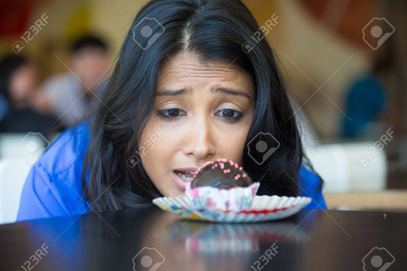 Closeup portrait of desperate woman in blue shirt craving fudge with pink sprinkles dessert, eager to eat, isolated indoors background - 51897791 Closeup portrait of desperate woman in blue shirt craving fudge with pink sprinkles dessert, eager to eat, isolated indoors background - 51897791