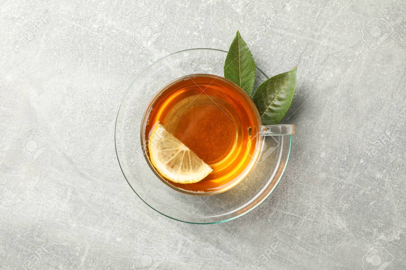 Cup of tea, mint and lemon on grey background, top view - 130085541 Cup of tea, mint and lemon on grey background, top view - 130085541