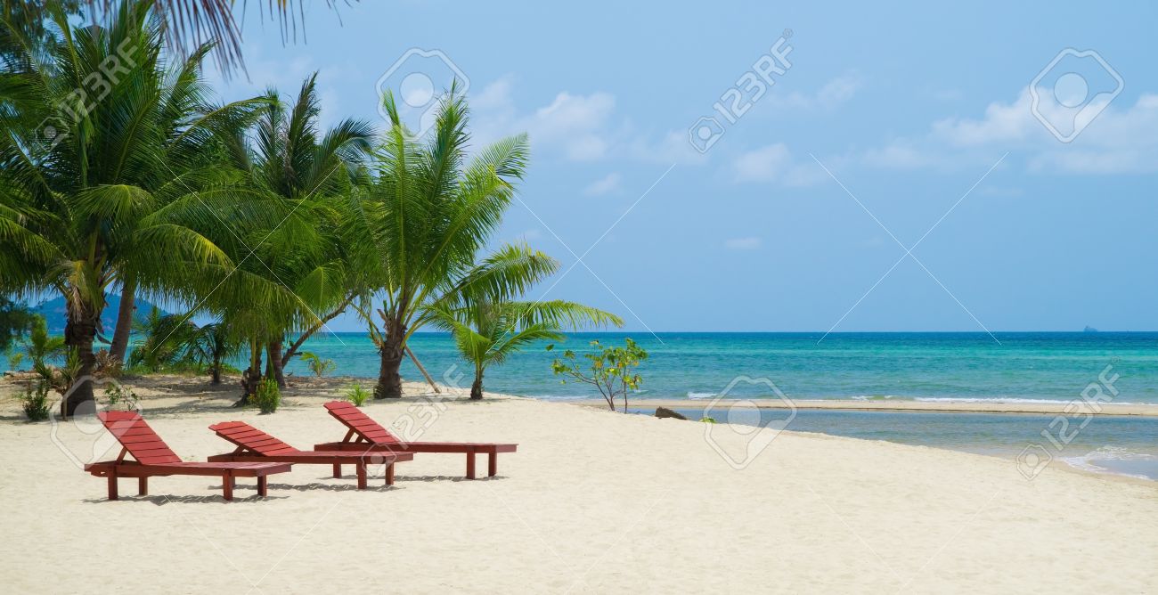 three red wooden beach chairs on white sand against blue ocean