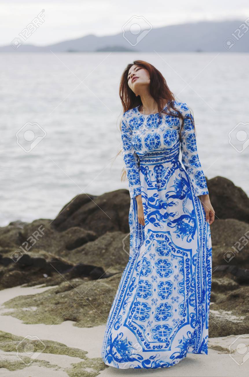 岩の多い海岸に夢を見て明るい青いドレスの女 の写真素材 画像素材 Image