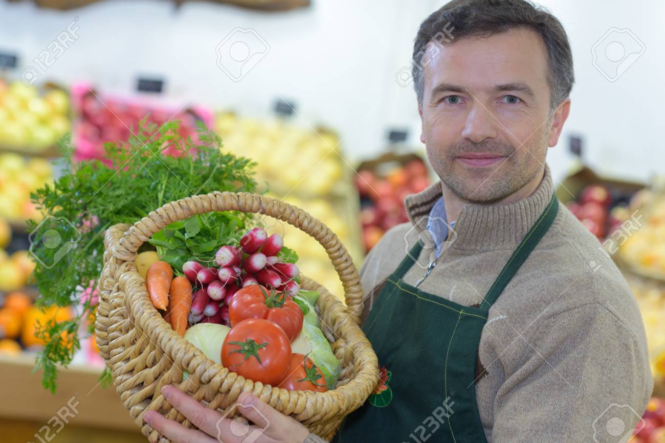 young grocery clerk posing in produce aisle of grocery store produce clerk