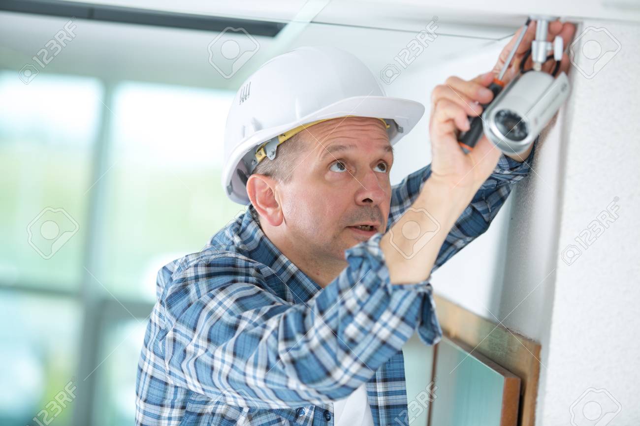 technician worker installing video surveillance camera on wall construction surveillance technician
