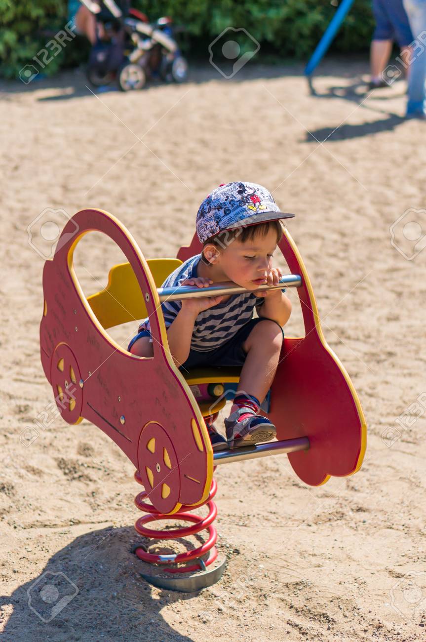 toddler boy with mickey mouse hat sitting on a red car shaped mickey mouse car for toddlers
