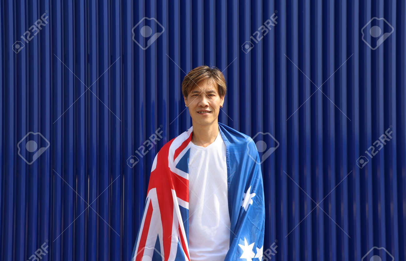 The man in white shirt with Australia flag on his shoulder on blue background. - 163875070 The man in white shirt with Australia flag on his shoulder on blue background. - 163875070