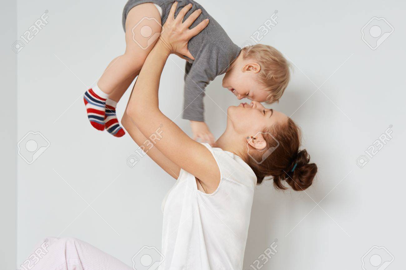 Portrait D Une Jeune Mere Aimante Jouant Avec Son Enfant Femme Ludique Tenant Un Petit Fils Mignon Au Dessus De Sa Tete Calme Soignante Maman En Tete Blanche Sur Le Front De Bebe Avec