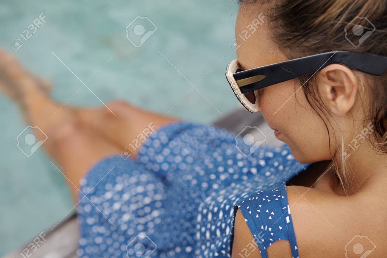 サングラスとスイミング プールでは水の中で水しぶき足座って青いドレスを着てきれいな日焼け肌を持つ若い妊婦の平面図をトリミングしました 妊娠中の女性のリラックス アウトドア の写真素材 画像素材 Image