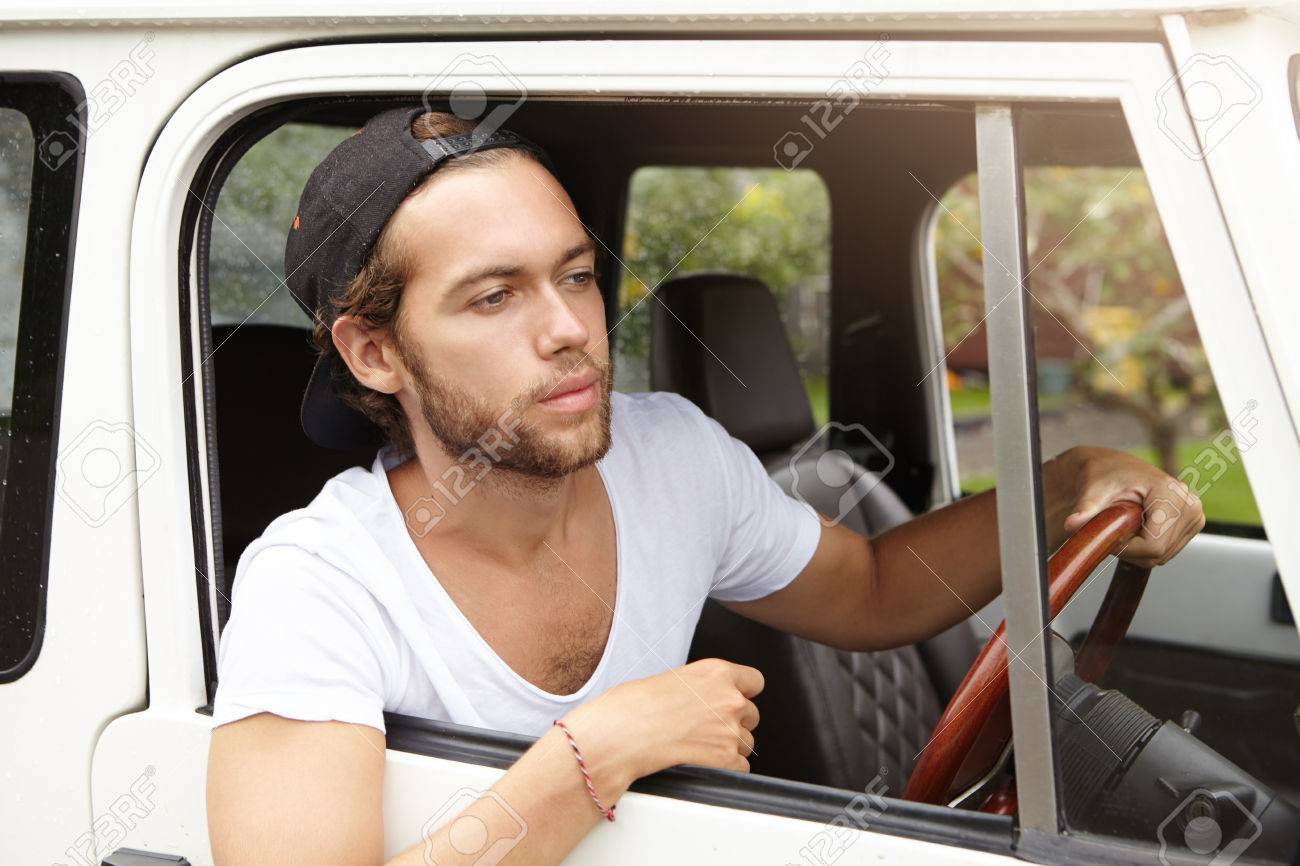 Apuesto Hombre Joven Sin Afeitar Llevaba Camiseta Casual Y Triste hombre que llevaba una gorra de béisbol mirando a