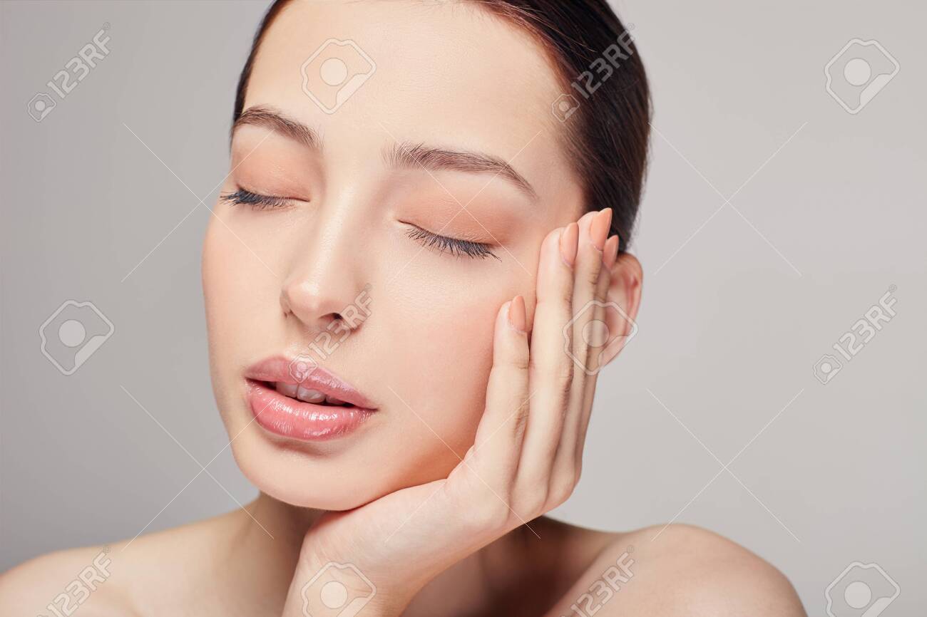 An elegant sophisticated beautiful girl with full lips, brown hair and clean delicate skin on the gray background. Lady put her head on her hand. Close eyes. Spa, face skin care. Wellness. - 134478597 An elegant sophisticated beautiful girl with full lips, brown hair and clean delicate skin on the gray background. Lady put her head on her hand. Close eyes. Spa, face skin care. Wellness. - 134478597