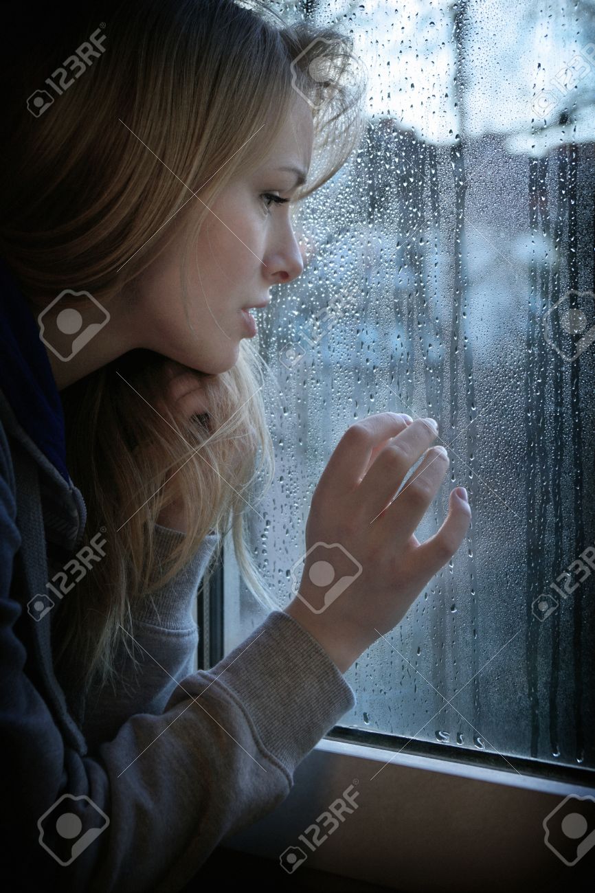 melancholic young woman looking through window with raindrops with added filter grain and vignette - 40911024 melancholic young woman looking through window with raindrops with added filter grain and vignette - 40911024