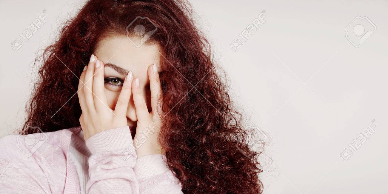 手で顔を覆っている彼女の指の間から覗く若い女性の恥ずかしい の写真素材 画像素材 Image