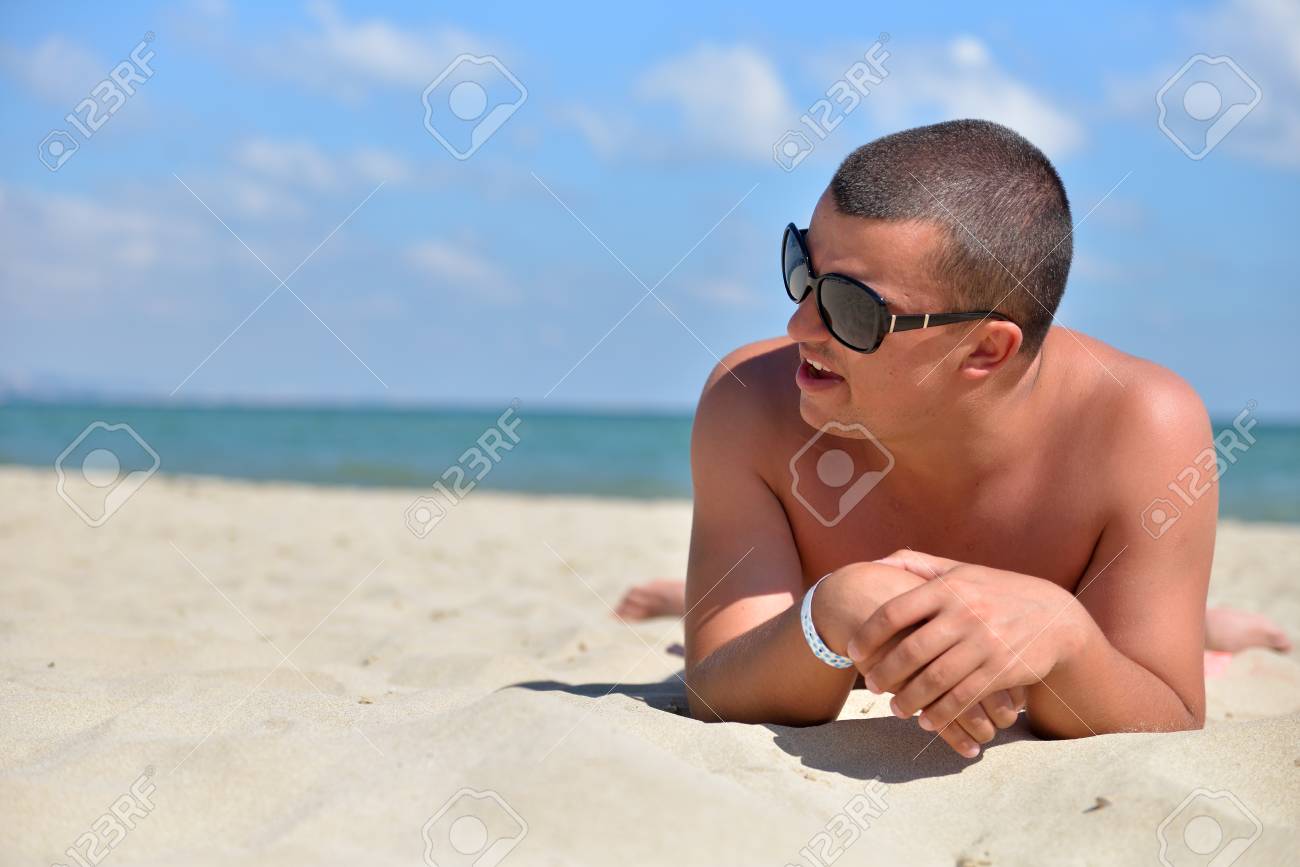 El Hombre Gafas De Sol En La Playa En La Arena Mirando A Lado. Varón Joven Que Disfruta De Vacaciones De Verano Los Viajes De Descanso En La Playa Por