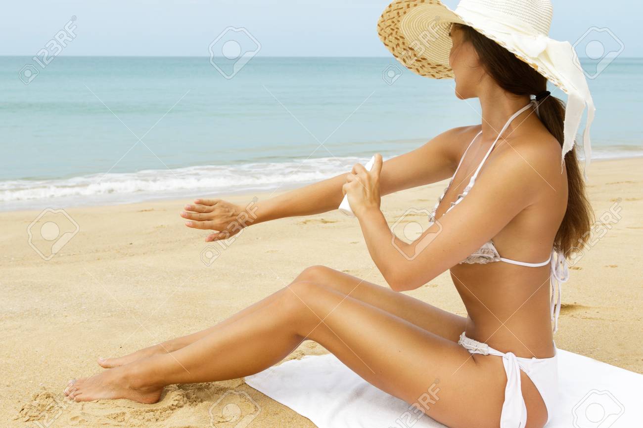 Beautiful Woman In Hat Sitting On The Beach And Applying Sunscreen.. Stock Photo, Picture And Royalty Free Image. Image 105351756.