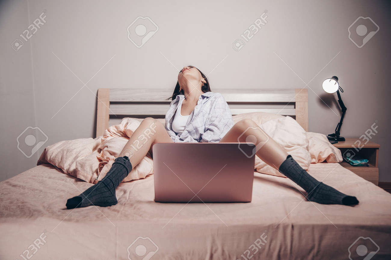 A Young Asian Webcam Model Girl Is Sitting In Front Of A Laptop With Her  Legs Spread. She Communicates And Shows Her Charms. Low Depth Of  Focus,artistic Photo Processing. Stock Photo, Picture