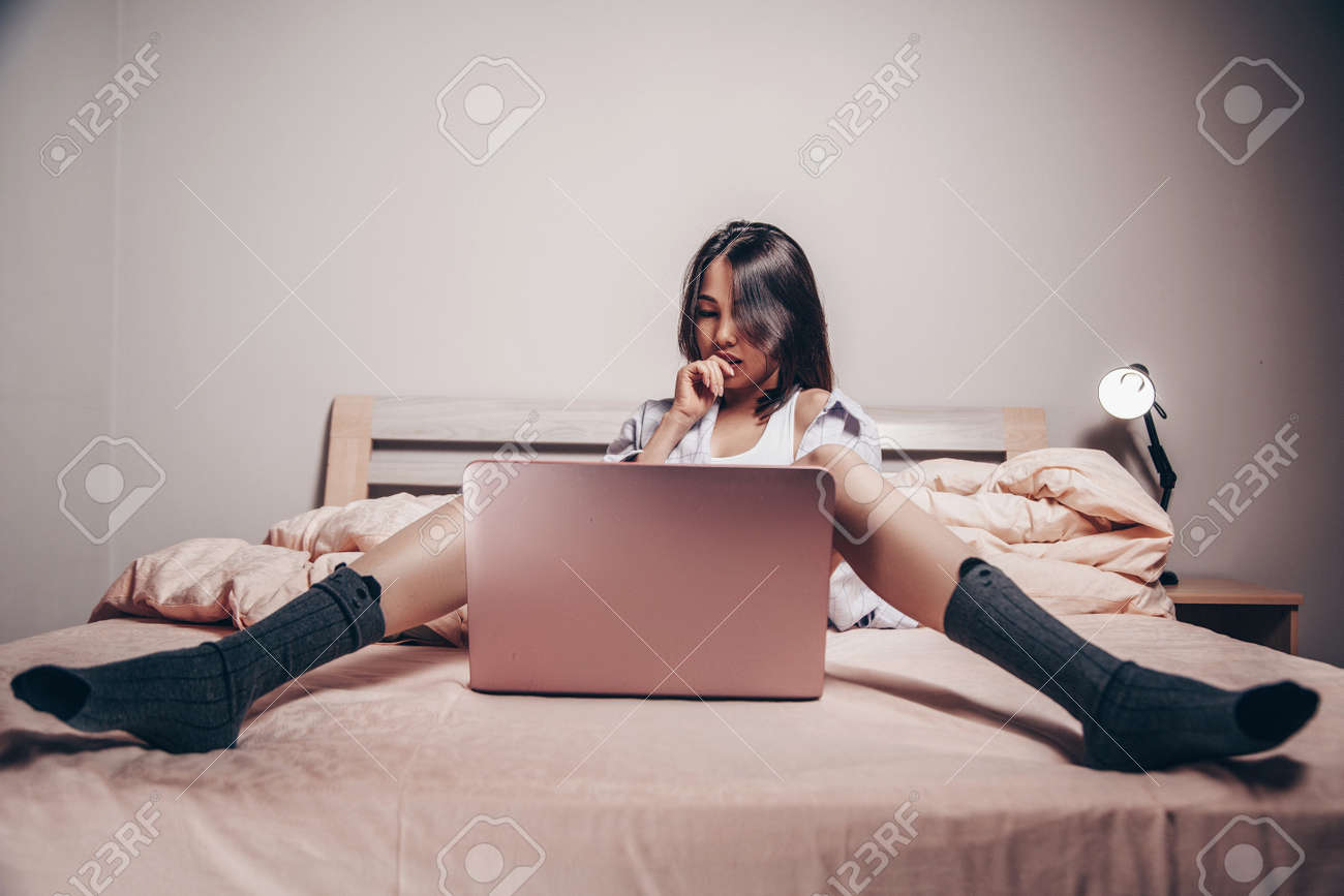 A Young Asian Webcam Model Girl Is Sitting In Front Of A Laptop. She  Communicates And Shows Her Charms. Low Depth Of Focus, Selective Focus  Stock Photo, Picture and Royalty Free Image.