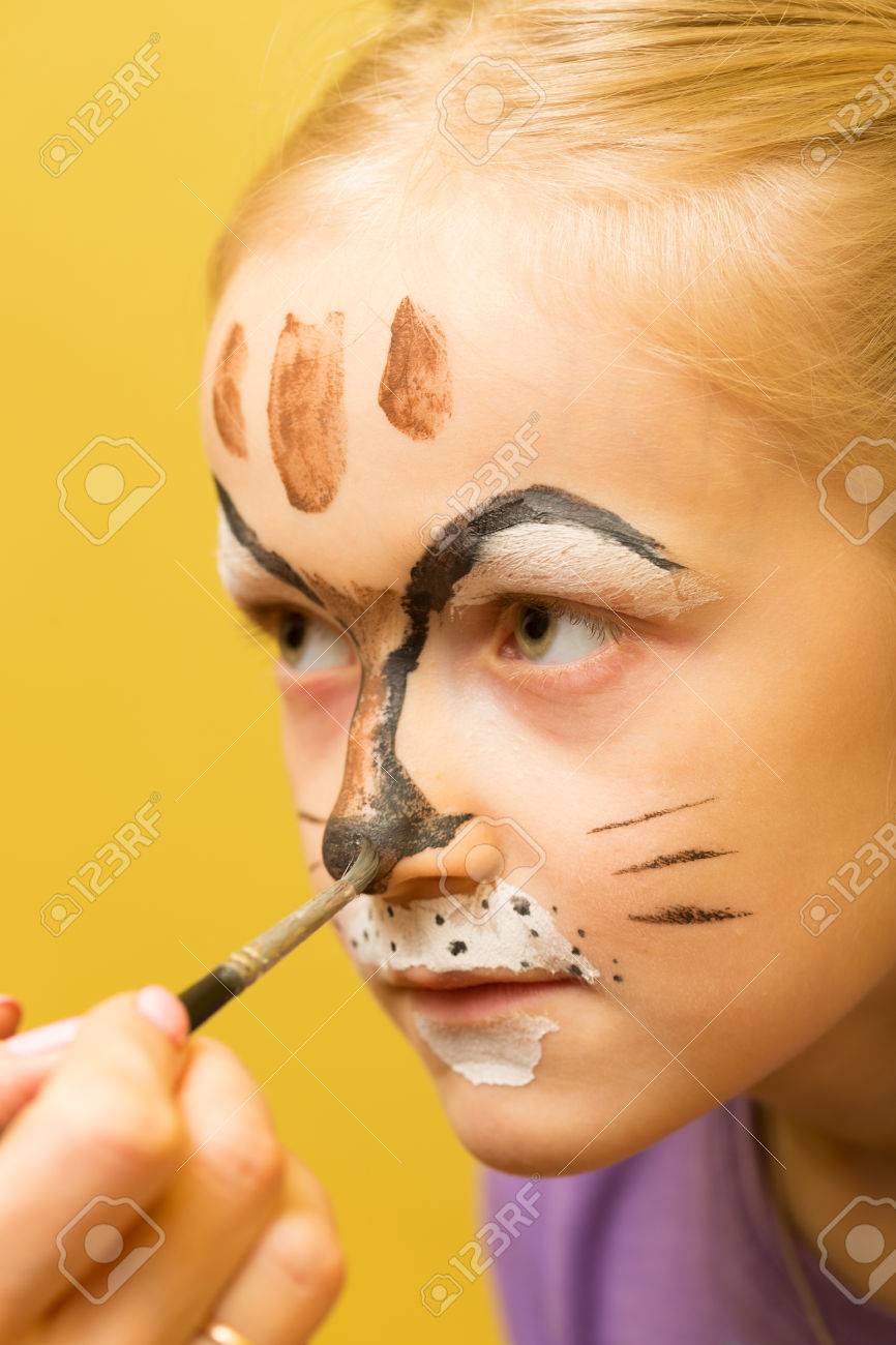 mother painting a face of her daughter like girl cat