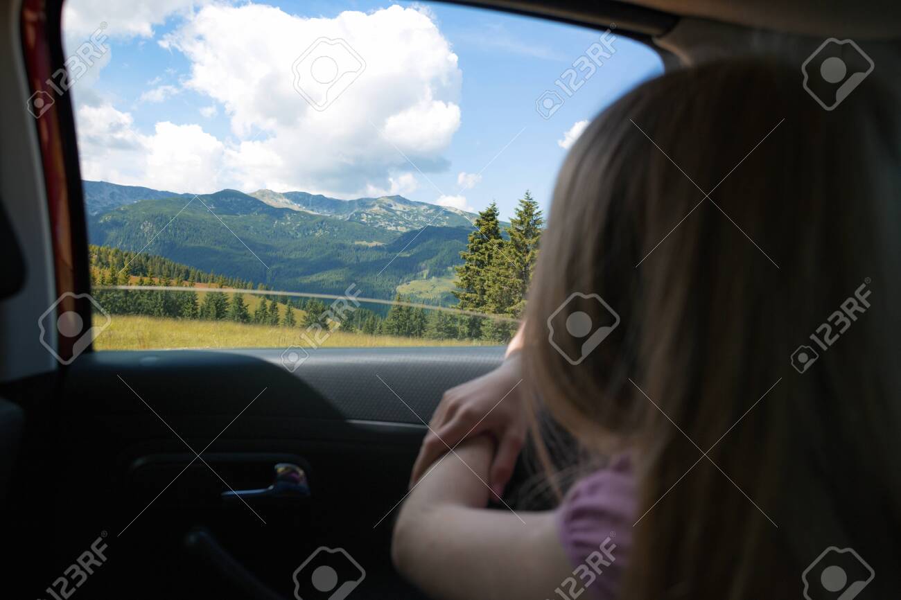 Summer Road Trip. Happy beautiful girl traveling in a car across at the mountains. Romania - 129685084 Summer Road Trip. Happy beautiful girl traveling in a car across at the mountains. Romania - 129685084