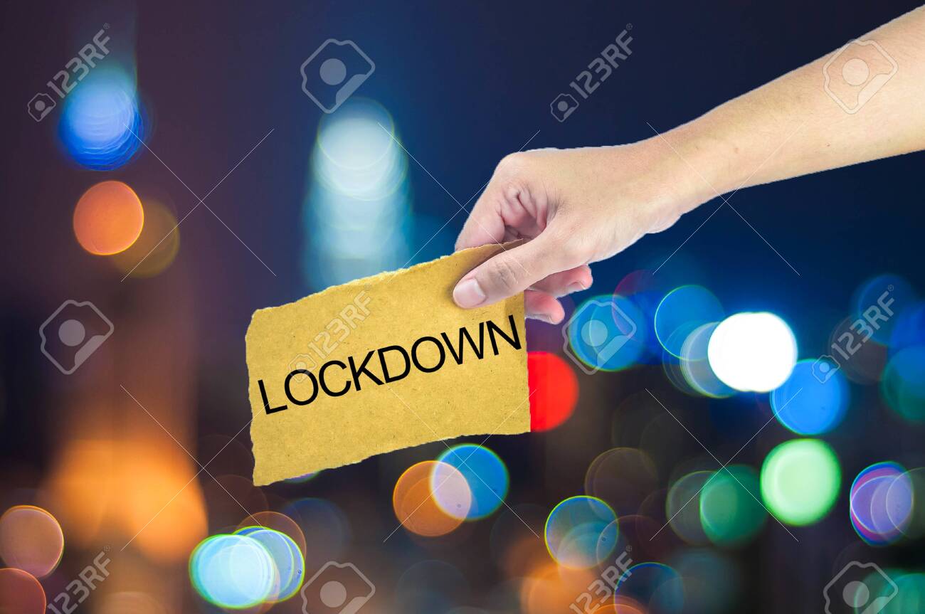 Hand holding a words have LOCKDOWN with city light bokeh as background - 143214739 Hand holding a words have LOCKDOWN with city light bokeh as background - 143214739