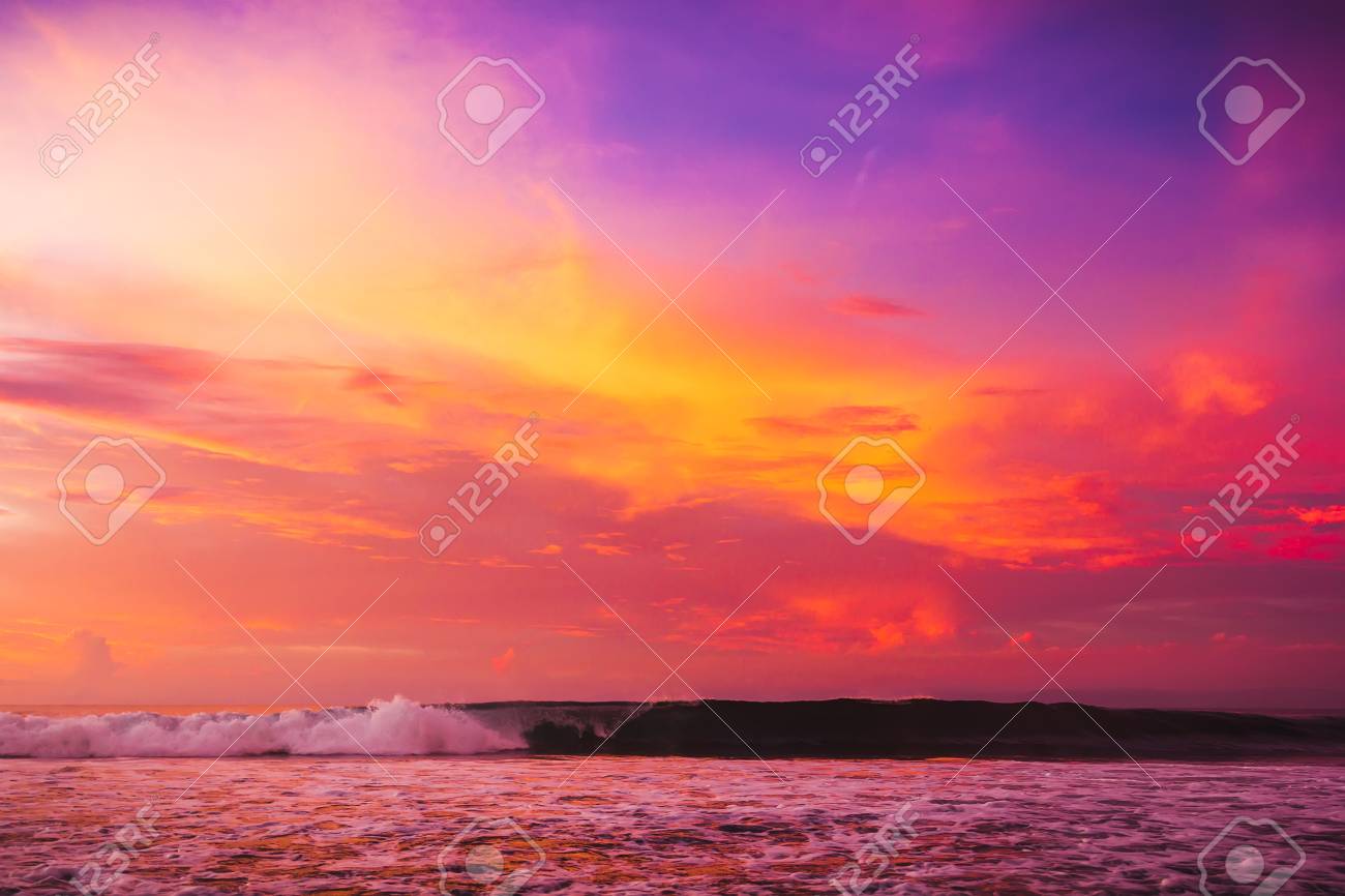 waves in the ocean at bright pink sunset or sunrise ocean with