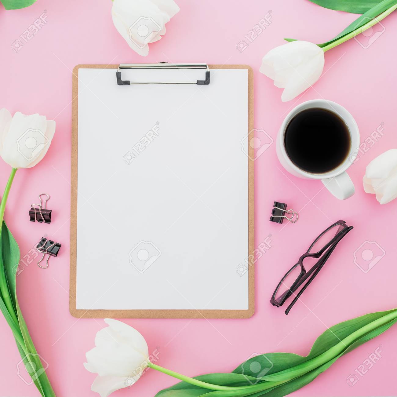 tulips flowers with mug of coffee clipboard and glasses on pink