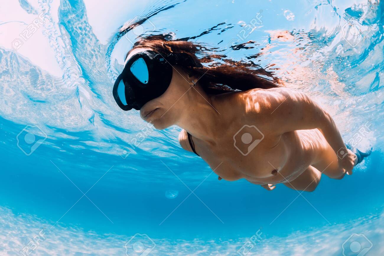 Naked woman free diver glides over sandy sea. Freediving in blue ocean - 129453454 Naked woman free diver glides over sandy sea. Freediving in blue ocean - 129453454